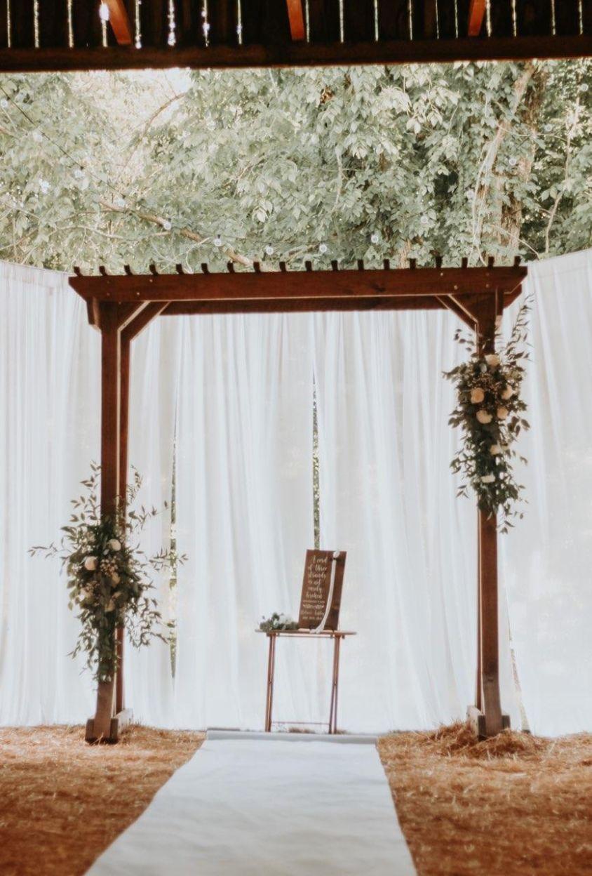 Photo of Ashley and Nolen Dale wedding alter with white sheer curtains and barn doors open to the wooded yard