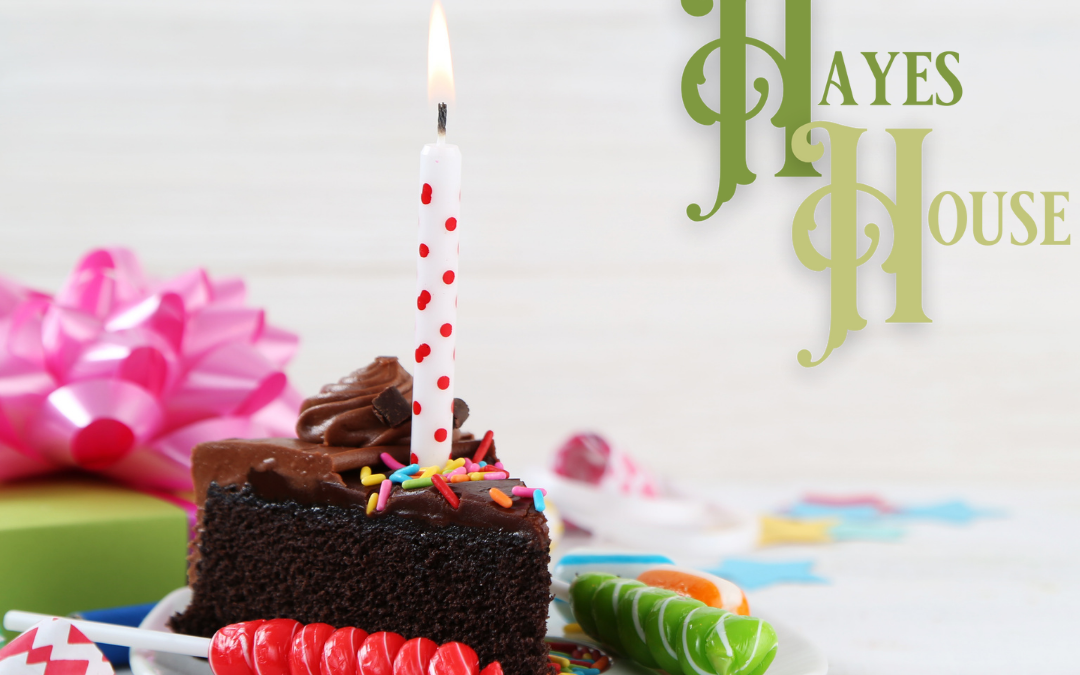 Photo of a slice of birthday cake with a candle and presents in the background with the Hayes House logo