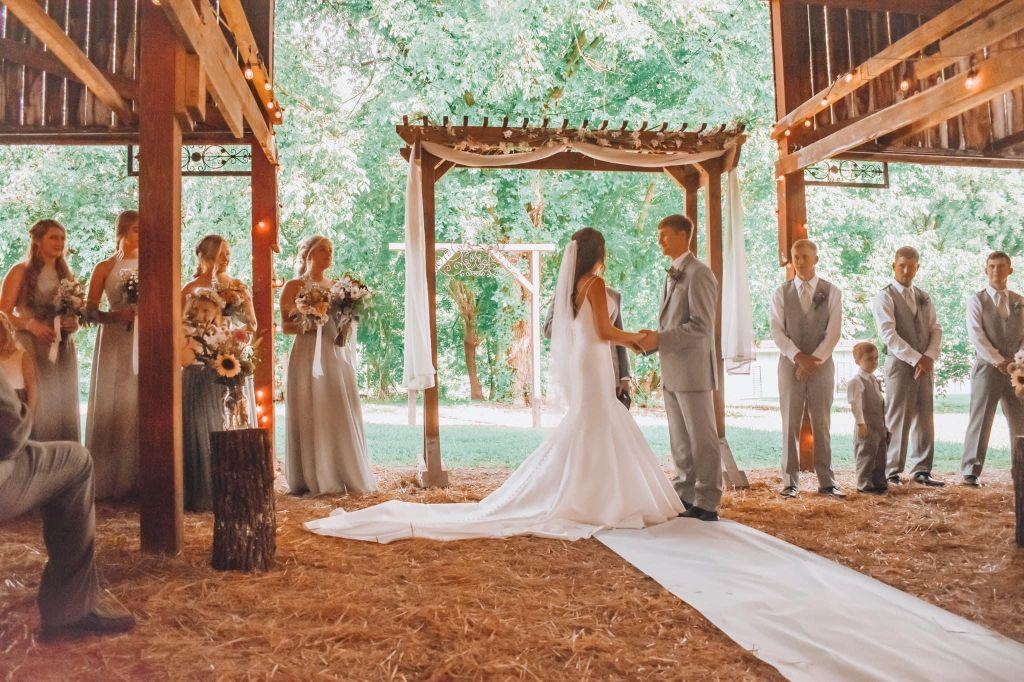 Burks wedding - photo of wedding ceremony with attendants and bridal couple against the open barn doors
