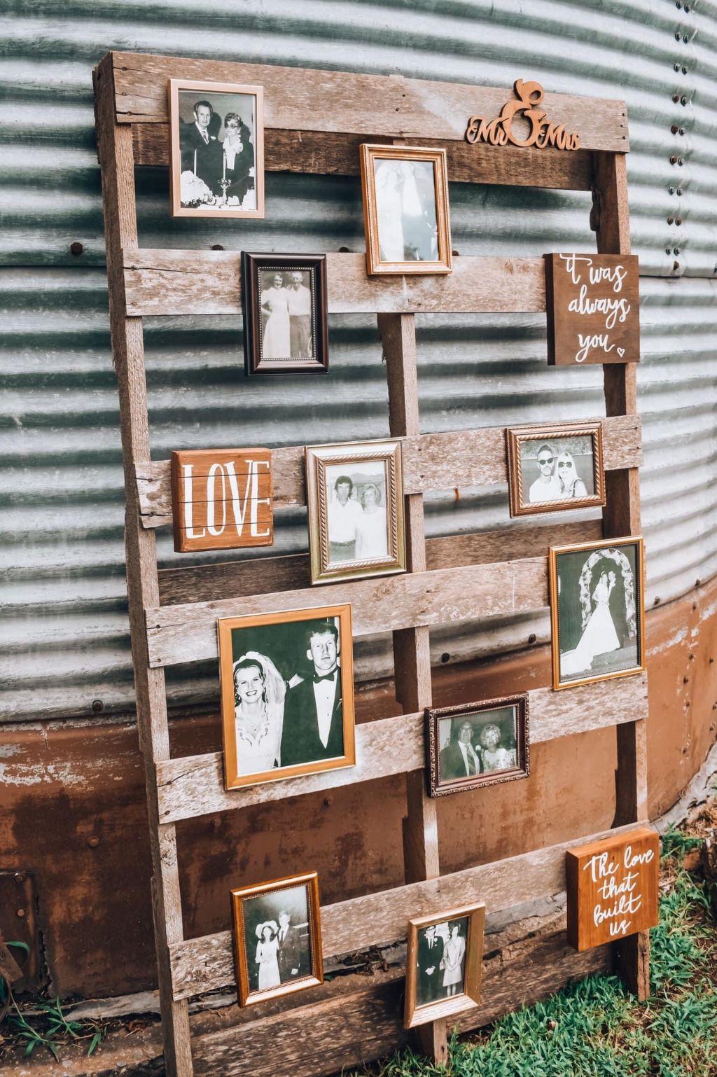 Burks Wedding - Photo arrangement of Bride/Groom family wedding photos on rustic board leaning against silo