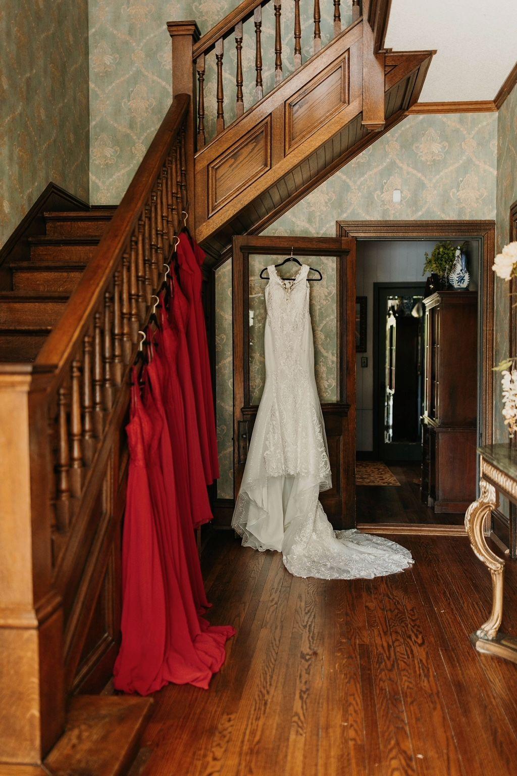 Photo of bridesmaids dresses and bride's dress hanging down the historic wood staircase of the Hayes House