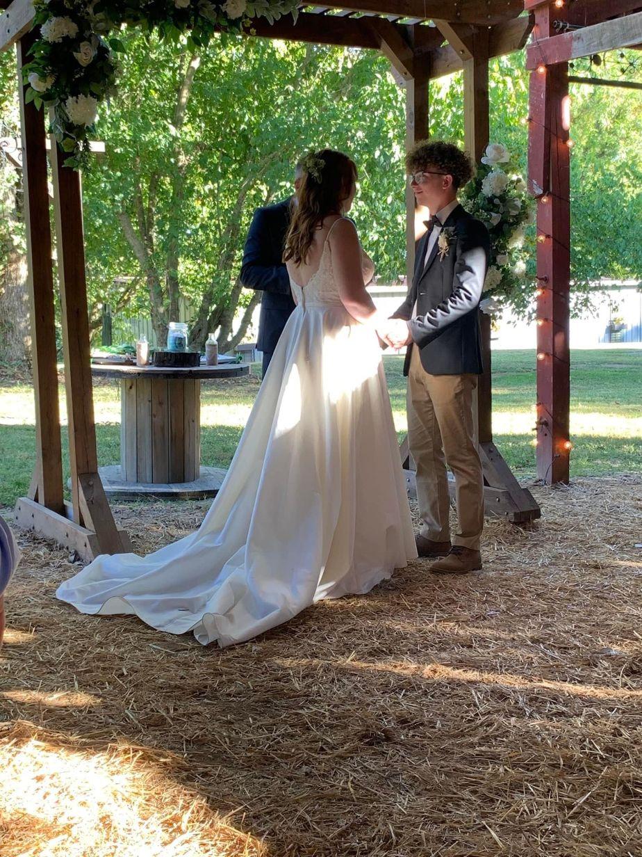 Madison and Dylan are framed by the lush October green space with the barn doors open for their wedding.