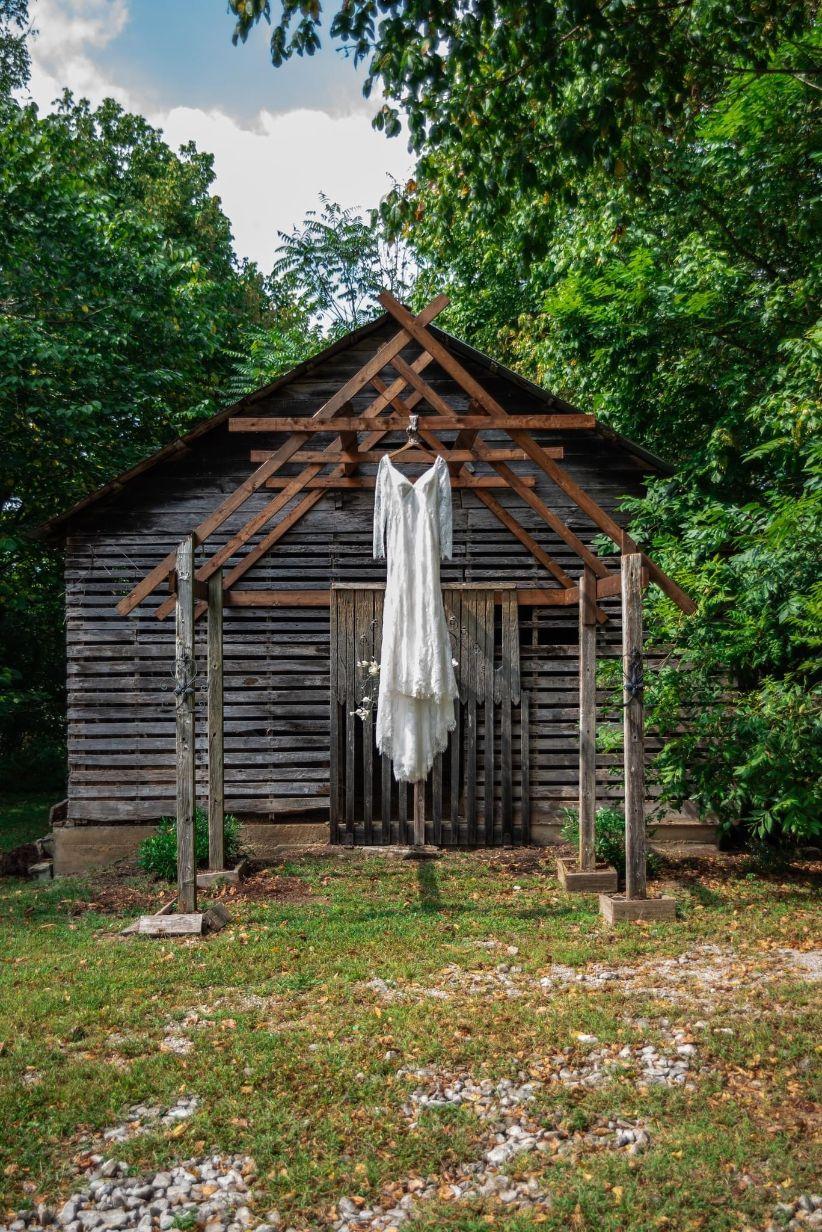 The wedding dress hanging in font of one of the historic outbuildings at Hayes House